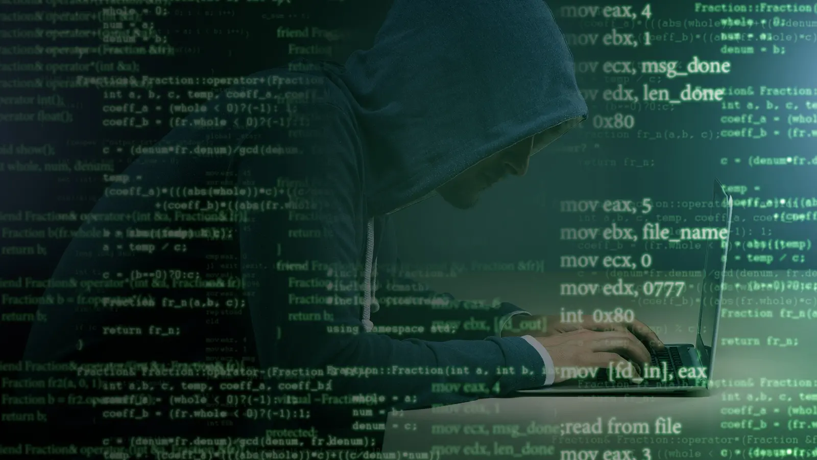 overlay of green code on person wearing hoodie furtively working on laptop