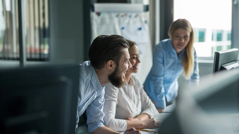 People smiling leaning on desk looking at computer monitor