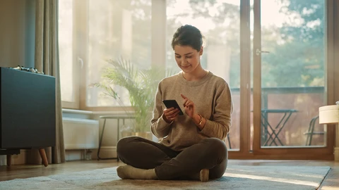Woman sitting cross legged looking at phone.