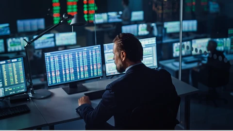 Male in suit reviewing data on monitors in data center