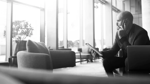 Man on phone with tablet in his hand.
