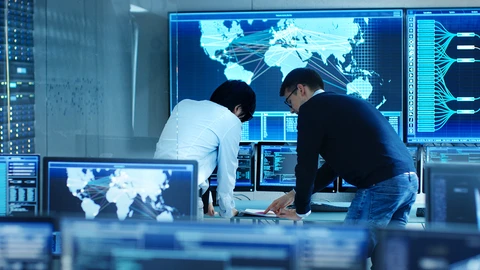 2 mean standing reviewing data in a Network Operations Center.