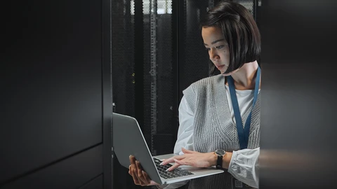 Professional Woman looking over laptop in datacenter