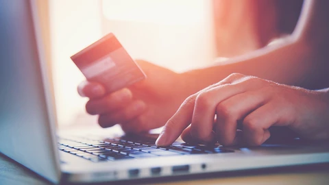 Hands typing on laptop holding a credit card