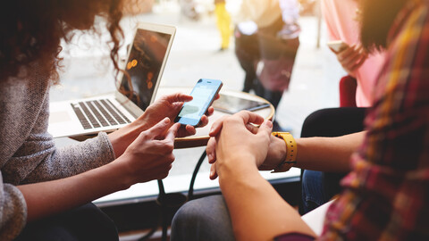 Two people sitting at a small table looking at a mobile phone