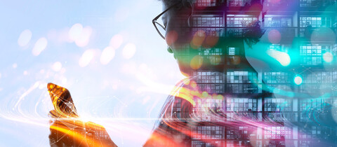 Person holding cell phone with high rise office building lite up at night and a colorful expressway embedded through page
