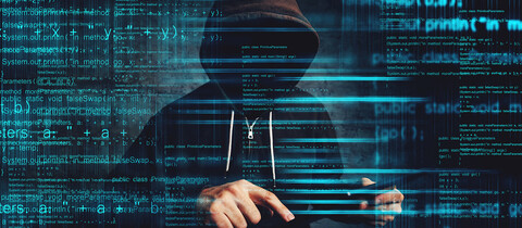 person in hoodie in front of laptop