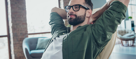 IT Worker sitting in chair with arms crossed behind his head.