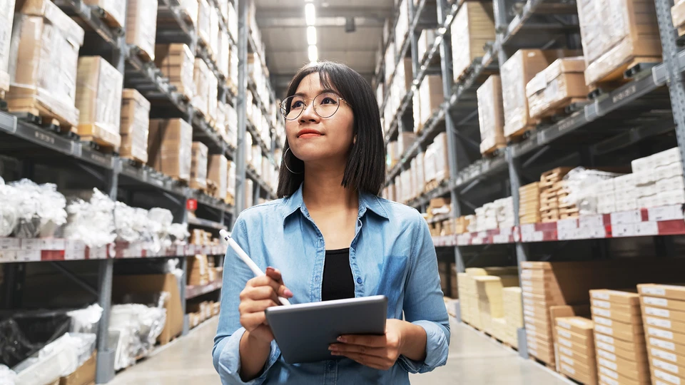 Woman With Clipboard walking thru Warehouse Shelving