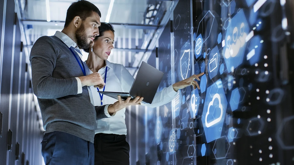 2 people in datacenter reviewing information on laptop.